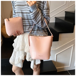 Detail of pink croc-embossed bucket bag and matching pouch with textured leather finish