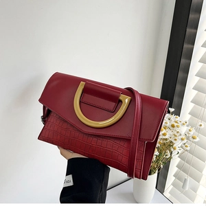 Detail of wine red crocodile embossed clutch bag with vintage gold D-ring buckle