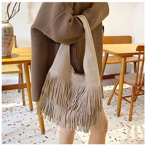 Detailopname van beige suède schoudertas met modieuze franjes en bohemien stijl