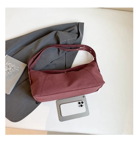 Close-up of deep red frosted dumpling bag with rivet handles and sleek urban design