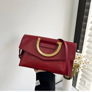 Detailed close-up of dark red crocodile pattern handbag with golden D-shaped metal buckle