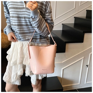 Detail of pink faux crocodile leather bucket bag with embossed logo and textured surface