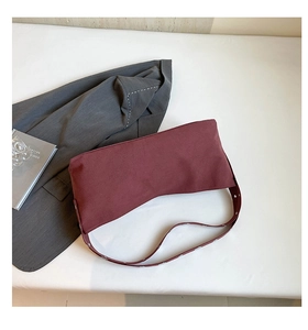 Detail of burgundy vintage crossbody bag with silver rivets on a white background