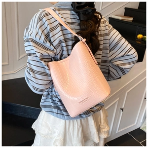 Detailed close-up of pink crocodile texture bucket bag with gold fashion lettering logo