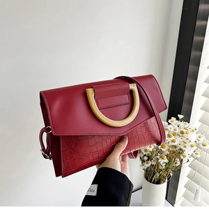 Close-up of dark red evening clutch bag with crocodile texture and gold metal ring detail