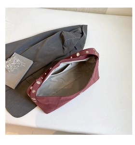 Macro shot of retro burgundy dumpling bag with silver studs and a zippered interior pocket