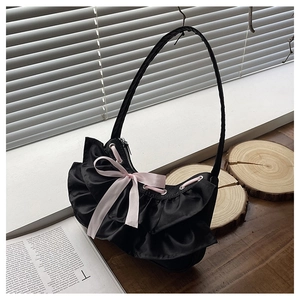Close-up of black satin underarm bag with ruffled pleats and a pink silk bow detail