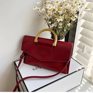 Detail of burgundy crocodile-embossed handbag featuring a resin semi-circle handle