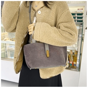 Detail view of suede tote bag featuring a gold oval clasp and fine leather shoulder strap