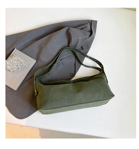 Detailed macro view of olive green suede shoulder bag with silver rivet strap accents