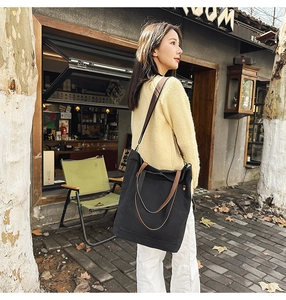 Detail of a large black vintage canvas tote bag with brown leather contrast straps