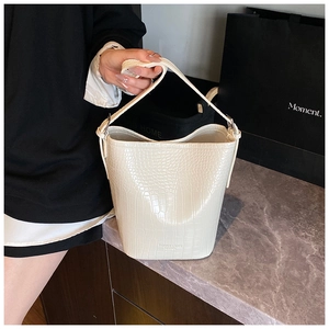 Detail showing the creamy white crocodile embossed leather texture on a bucket bag