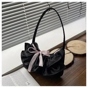 Detail of black ruffled shoulder bag with pink satin bow and sleek metal zipper closure