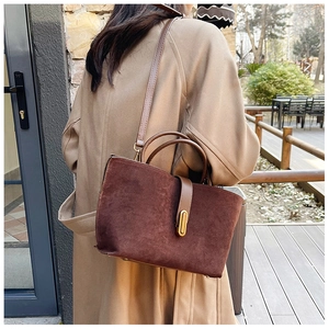 Outdoor shot of dark brown suede tote bag with metallic clasp worn with a beige coat