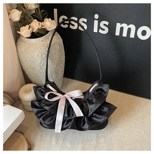 Detail of black satin crescent bag featuring wave pleats and a soft pink silk bow accent