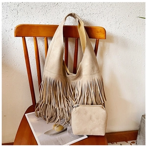Detailopname van beige suède schoudertas met lange franjes en bijpassend klein tasje