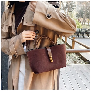 Close-up of vintage brown suede tote bag with golden metal clasp and twin handles