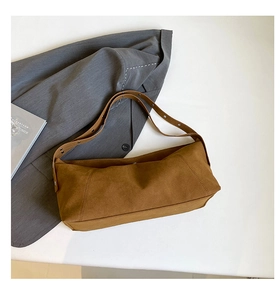 Detail view of brown matte leather shoulder bag with adjustable strap on grey blazer