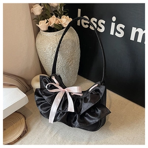 Detail of black satin hobo bag with pink ribbon bow and ruffled edges in a lifestyle setup