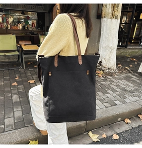 Detail of vintage canvas tote bag featuring large front pocket and metal rivet accents