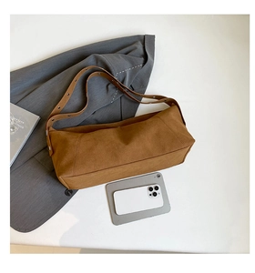 Close-up of brown suede crossbody bag showing the metallic eyelets and interior space