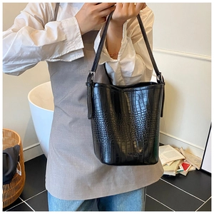 Detailed close-up of black crocodile pattern leather texture and embossed logo on bucket bag