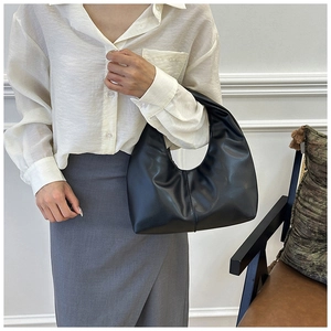 Bolso de hombro de media luna negro minimalista en cuero liso mostrado en modelo