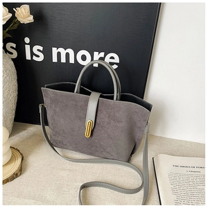 Detailed close-up of a vintage grey suede tote bag with gold metal buckle and smooth leather handle
