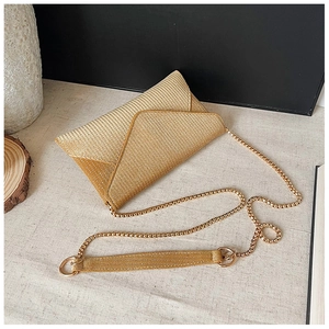 Detailed view of champagne envelope clutch bag with glitter texture and gold chain strap