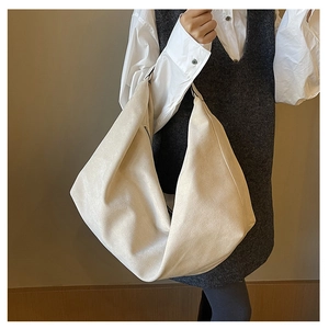 Close-up of a large beige suede hobo bag featuring a black zipper and slouchy texture