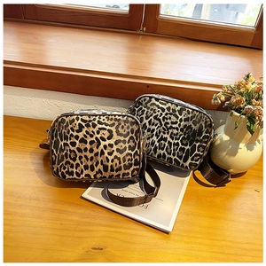 Détails de sacs bandoulière à motif léopard en marron et gris sur table en bois
