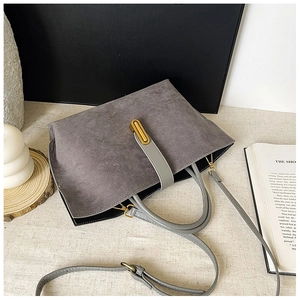 Detail view of grey frosted tote bag featuring a sleek gold metal buckle and strap