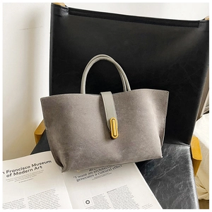 Detail of grey suede tote bag with golden metal buckle on black leather chair