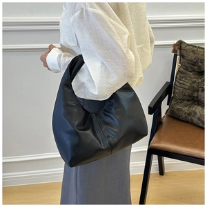Primer plano de un bolso croissant de cuero negro con textura suave y estilo minimalista