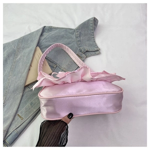 Detail of light pink satin handbag featuring large ruffle edge and feminine texture
