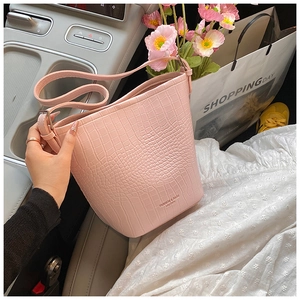 Detailed view of pink crocodile pattern bucket bag with strap on car seat with flowers