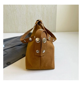 Detail of caramel suede crossbody bag featuring oversized silver metal rivets on the side