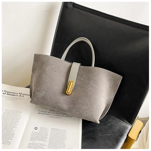 Detail of taupe matte leather tote bag with elegant gold metal buckle on a chair