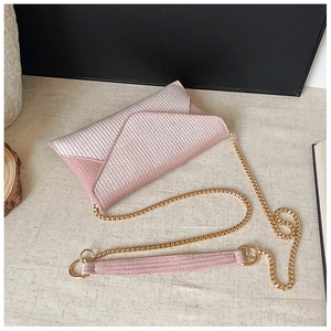 Detailed view of pink rhinestone envelope bag with golden chain strap on linen