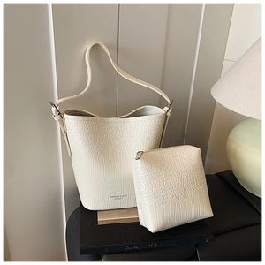 Close-up of crocodile pattern leather texture and metal buckle on cream bucket bag