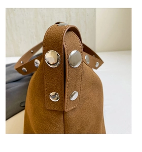 Detailed macro view of caramel brown suede texture and large silver metal studs on the bag