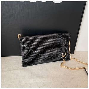 Close-up of black envelope chain bag with shimmering sequins and gold chain detail