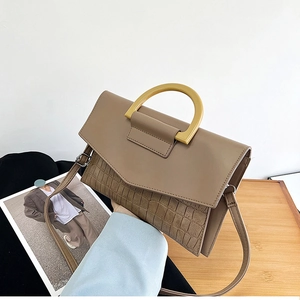 Detail of khaki crocodile texture handbag with yellow resin handle and thin strap