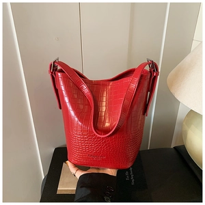 Detail of red crocodile pattern bucket bag with silver metal buckle and wide strap
