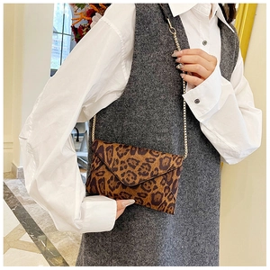 Leopard print envelope crossbody bag with gold chain strap shown on a model's shoulder