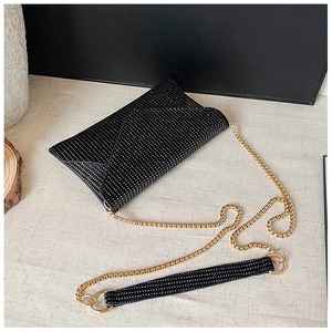 Macro detail of the rhinestone envelope clutch bag featuring gold chain strap and shimmer