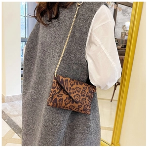 Lifestyle shot of leopard print envelope clutch with gold chain strap on a model