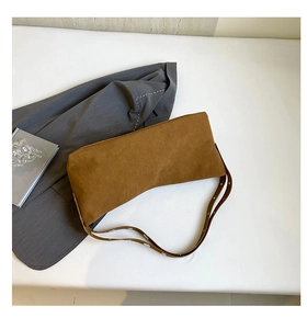 Detailed macro view of brown suede shoulder bag with industrial silver eyelet strap