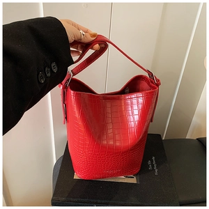 Close-up of bright red crocodile-embossed bucket bag with silver buckle and fashion logo