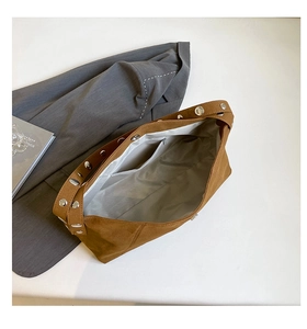 Detail view of the brown suede crossbody bag showing the interior compartment and silver studs
